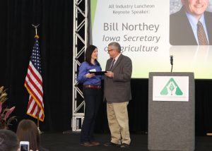 Amber Kohlhaas accepts an award on behalf of Hagie Manufacturing Company for the Water Quality Initiative Leader Award presented by Iowa Secretary of Agriculture Bill Northey